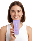 A smiling woman holding Hideaway. Aurora Rouge exfoliating body scrub