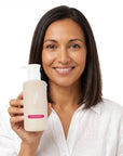 A smiling woman holding Hideaway. Aurora Rouge hand wash