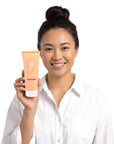 A smiling woman holding Hideaway. Aurora Rouge hair mask