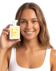 A smiling woman holding Hideaway. Chasing Sunlight perfume
