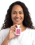 A smiling woman holding Hideaway. Cheeky Cherry perfume