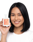 A smiling woman holding Hideaway. Cherry Blaze perfume