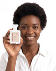 A smiling woman holding Hideaway. Coco Loco perfume