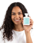 A smiling woman holding Hideaway. Diamond Kiss perfume