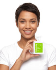 A smiling woman holding Hideaway. Lime Coconut perfume