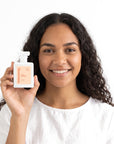 A smiling woman holding Hideaway. Main Squeeze perfume