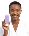A smiling woman holding Hideaway. Aurora Rouge mini shower mousse