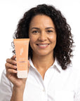 A smiling woman holding Hideaway. Black Essence mini hair mask