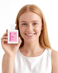 A smiling woman holding Hideaway. Pink Sunset perfume