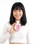 A smiling woman holding Hideaway. Strawberry Gelato perfume