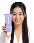 A smiling woman holding Hideaway. Vanilla Caramel body wash