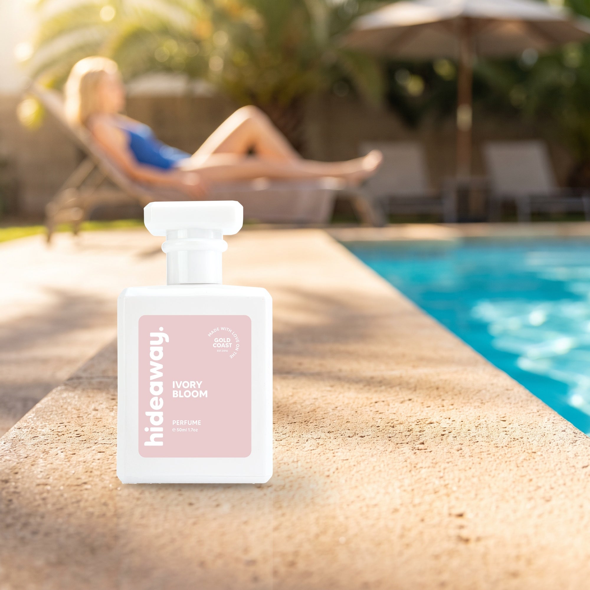hideaway. Ivory Bloom perfume 50ml bottle on a sunlit pool ledge on a summer afternoon