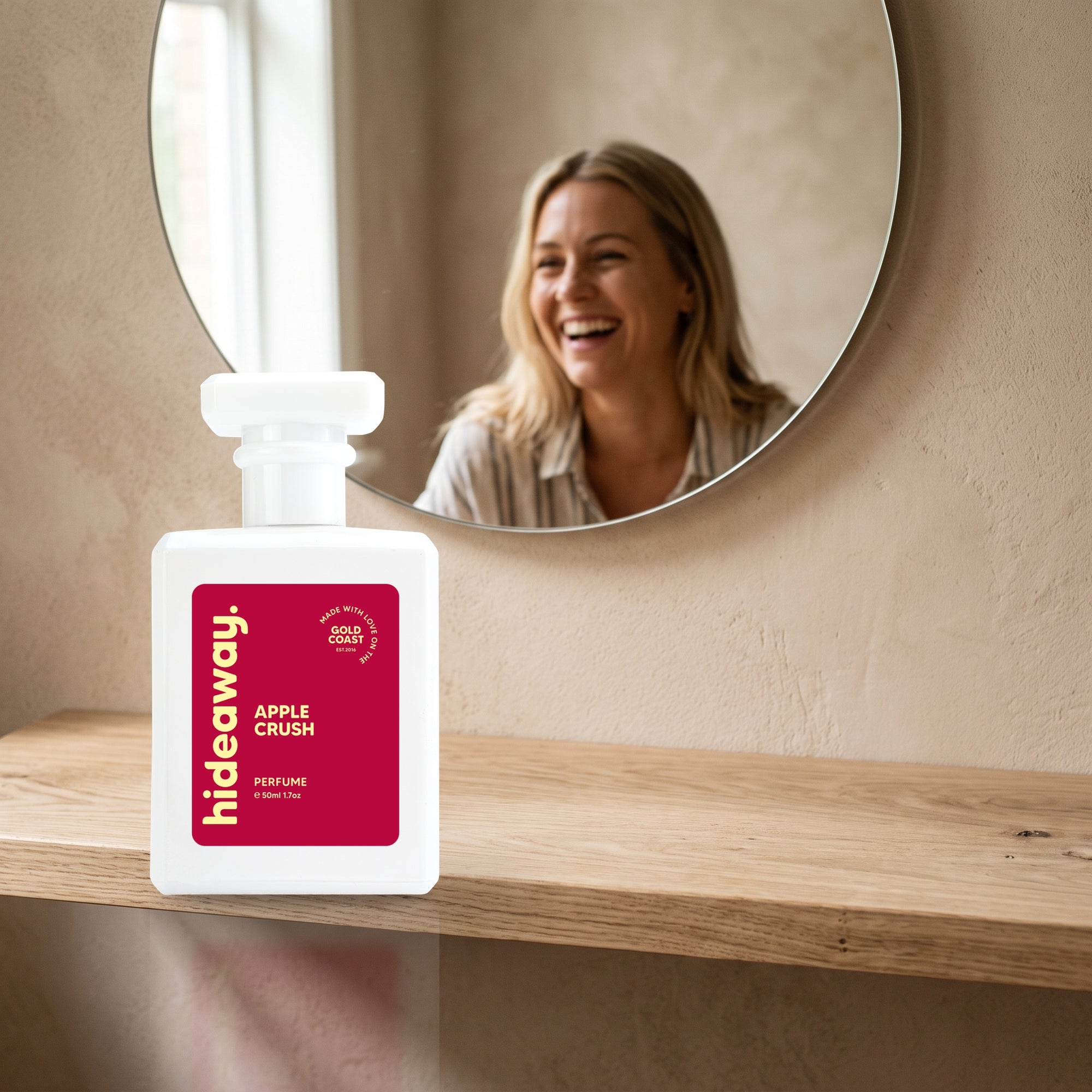hideaway. Apple Crush perfume 50ml bottle on an oak shelf below a round mirror