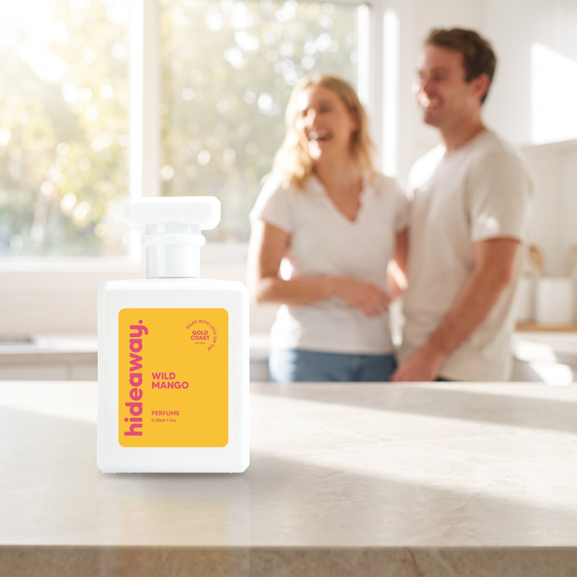hideaway. Wild Mango perfume 50ml bottle on a stone benchtop in a bright kitchen