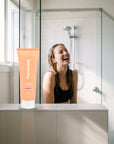 hideaway. Mini Black Essence Conditioner on a shower ledge in a bright bathroom