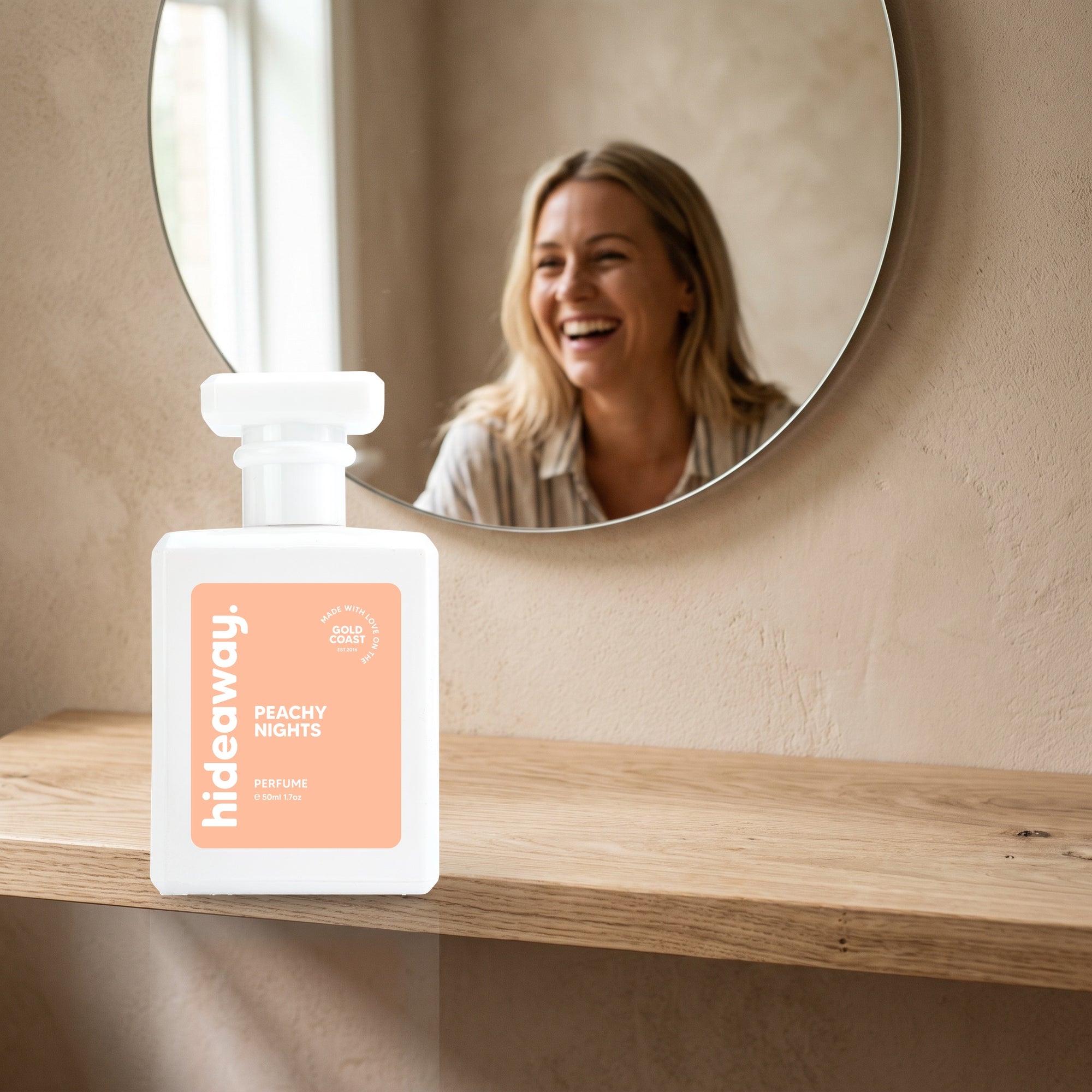 hideaway. Peachy Nights perfume 50ml bottle on an oak shelf below a round mirror