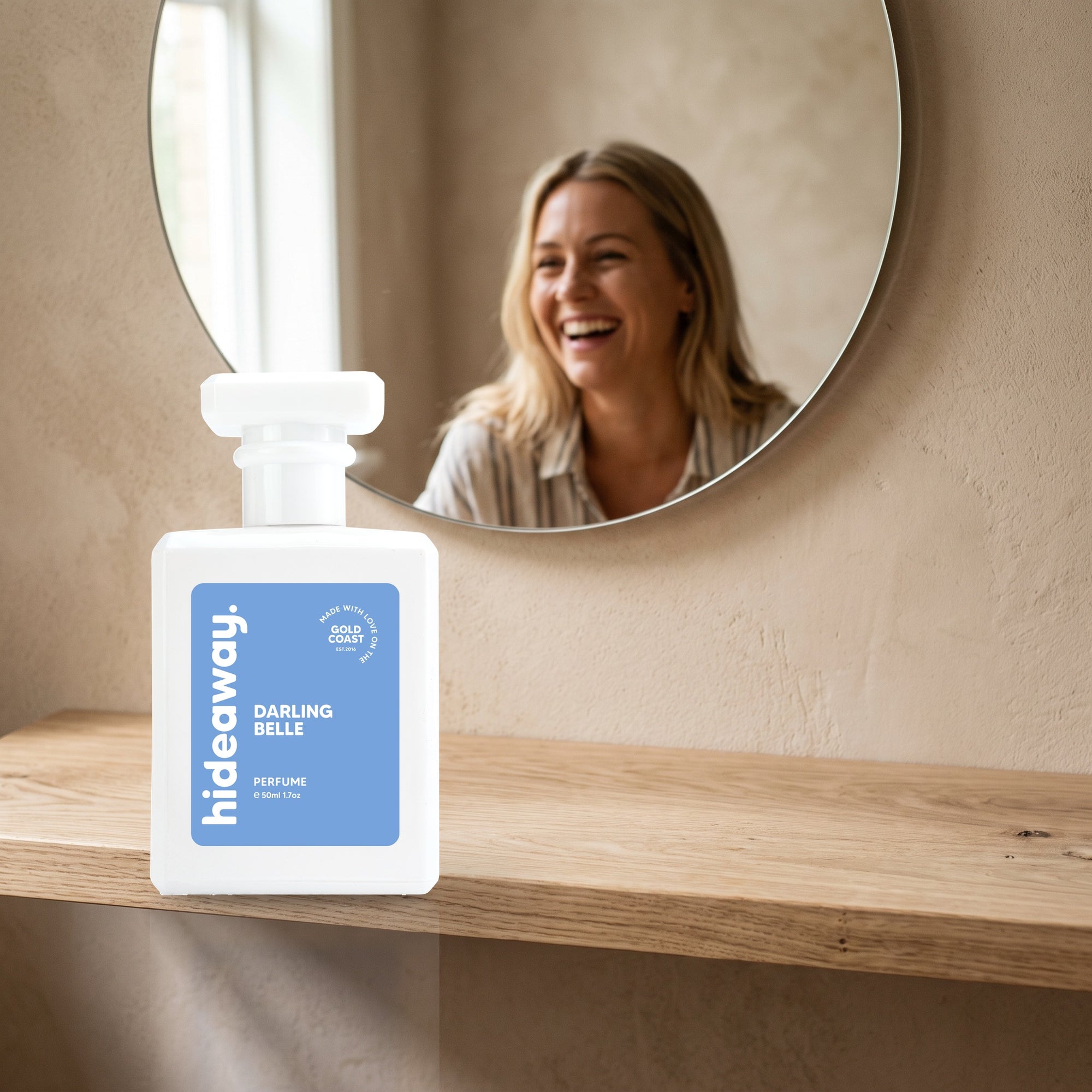 hideaway. Darling Belle perfume 50ml bottle on an oak shelf below a round mirror