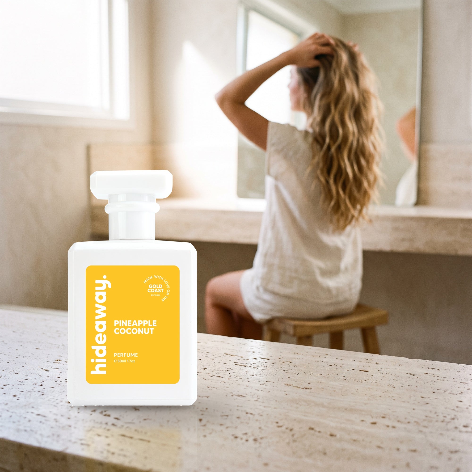 hideaway. Pineapple Coconut perfume 50ml bottle on a travertine vanity while she gets ready in the morning