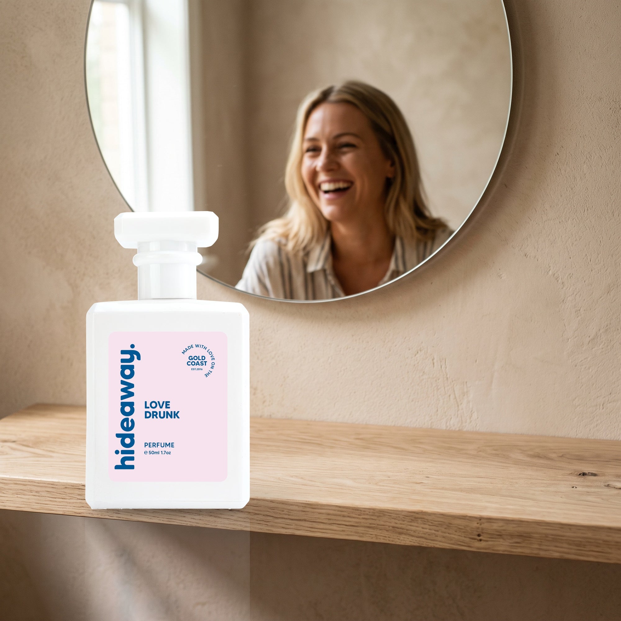 hideaway. Love Drunk perfume 50ml bottle on an oak shelf below a round mirror