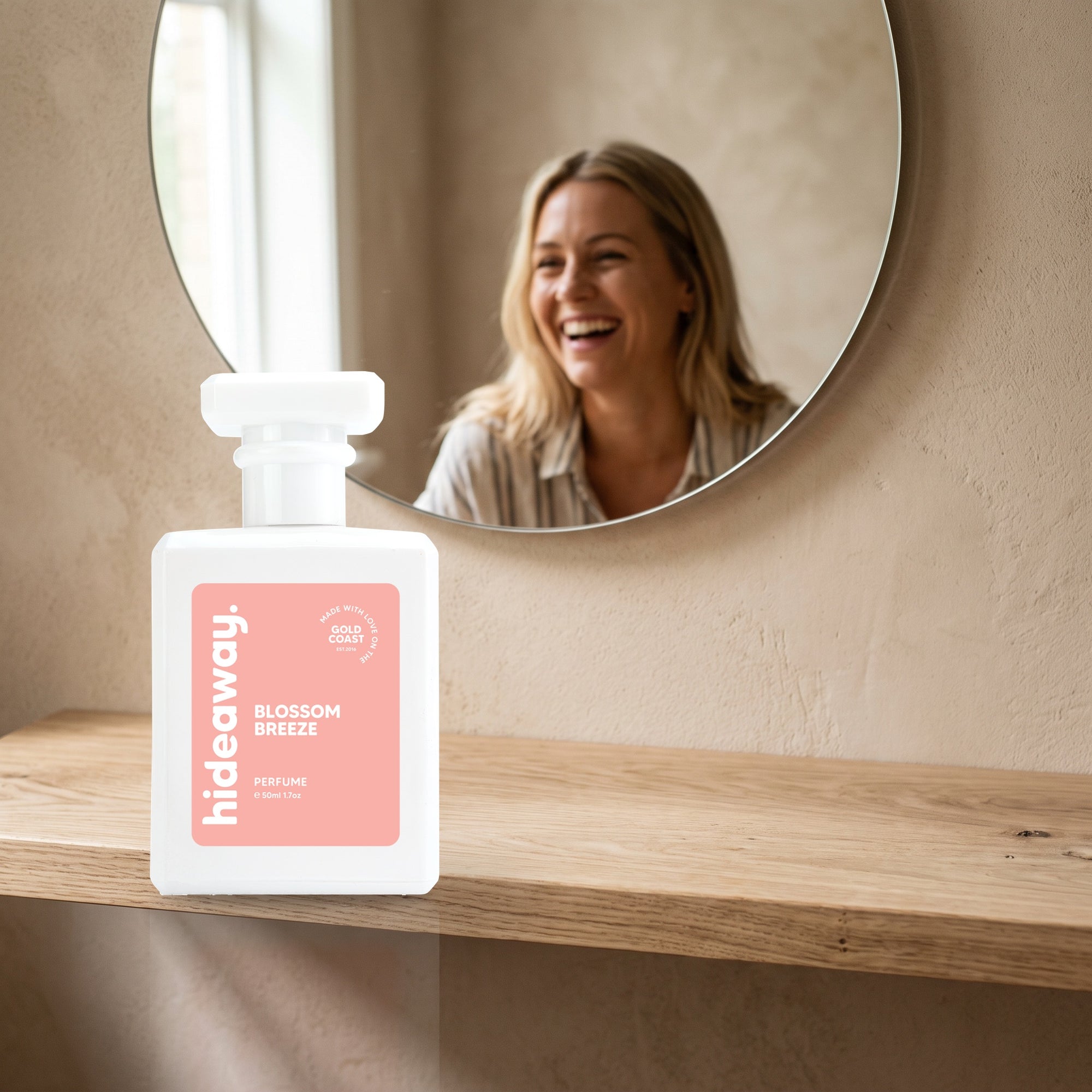 hideaway. Blossom Breeze perfume 50ml bottle on an oak shelf below a round mirror