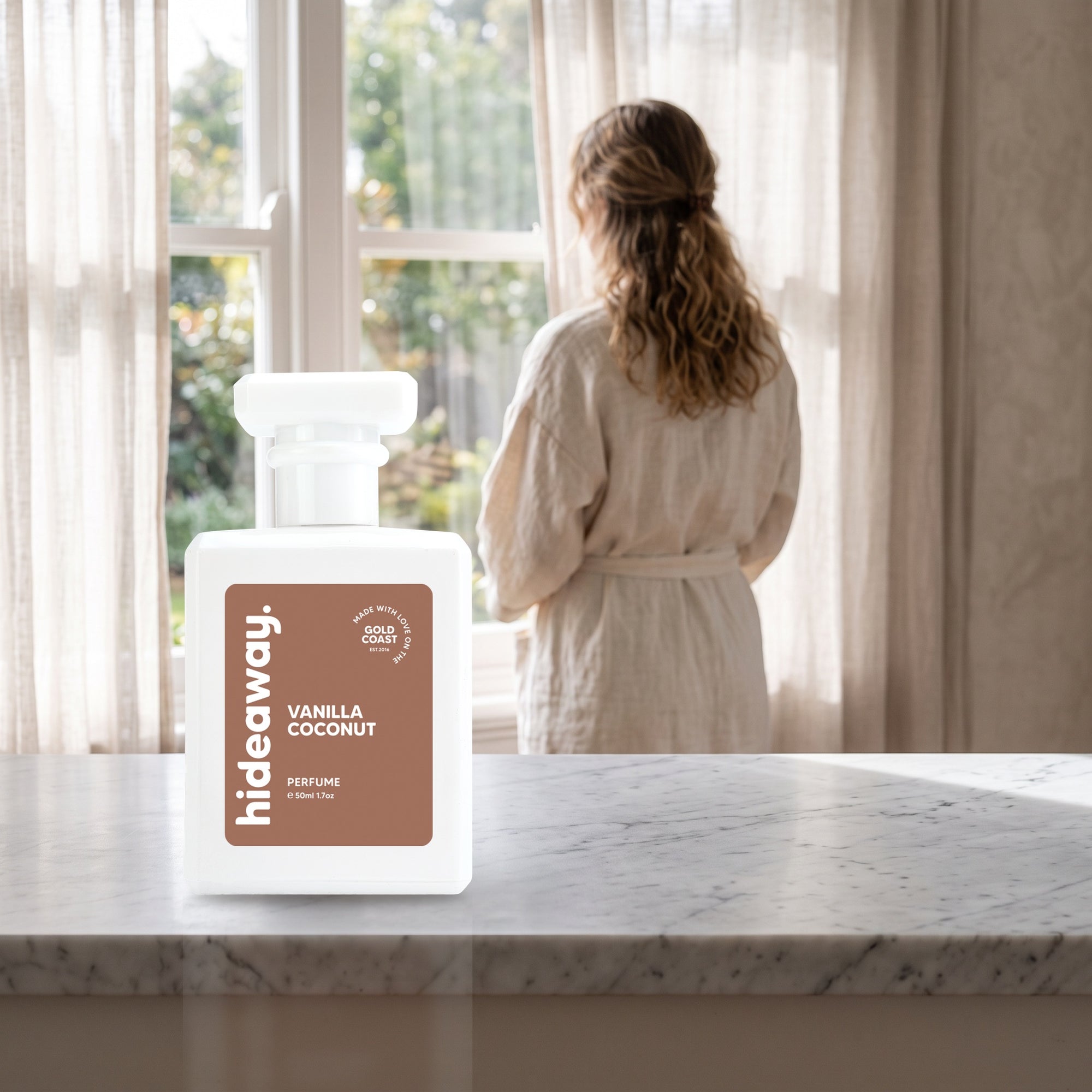 hideaway. Vanilla Coconut perfume 50ml bottle on a marble ledge by a sunlit window