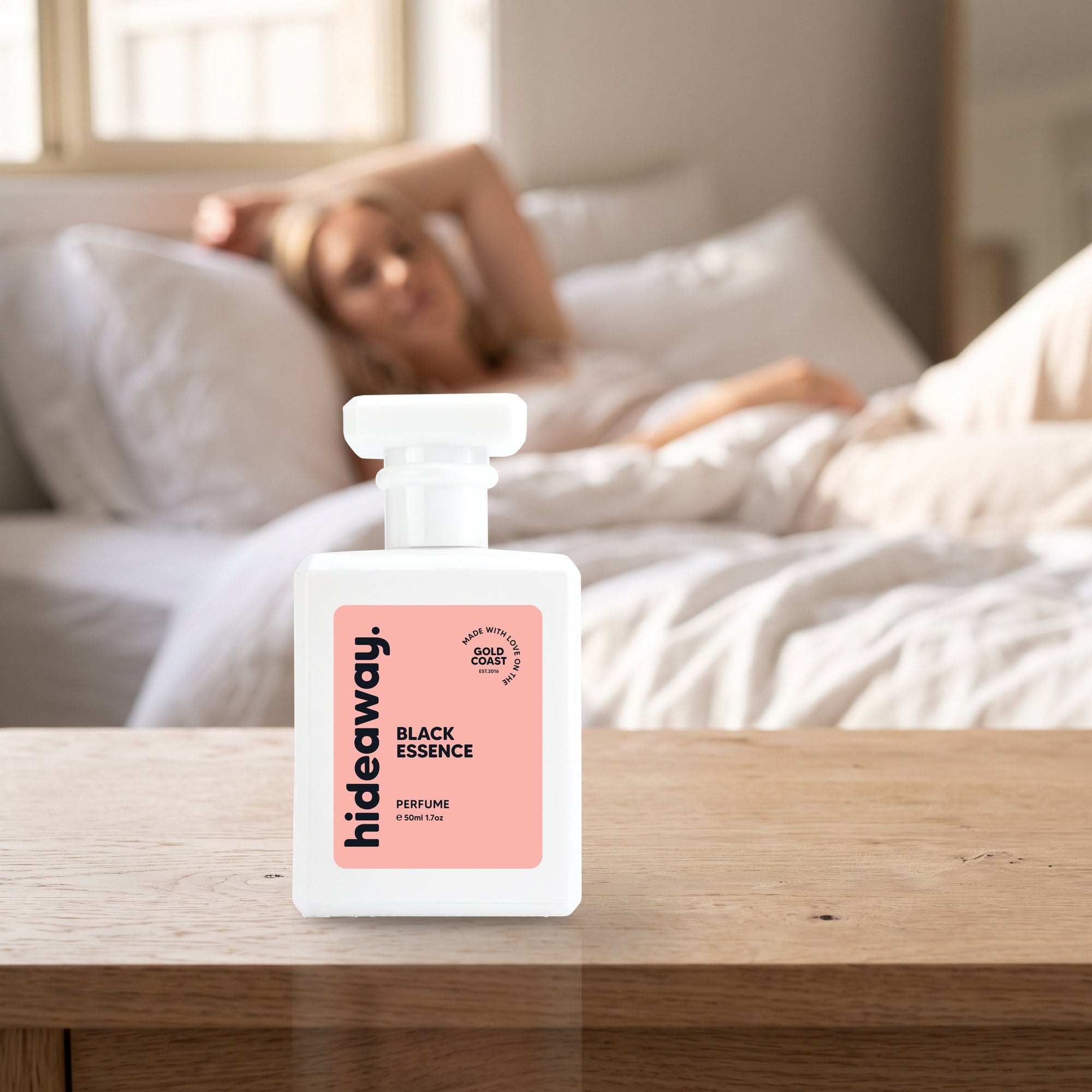 hideaway. Black Essence perfume 50ml bottle on a bedside table in warm morning light