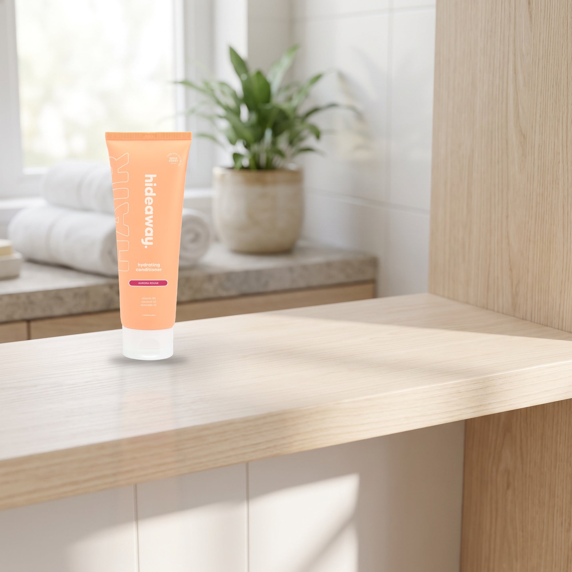 hideaway. Aurora Rouge Conditioner on a timber bathroom shelf beside rolled towels