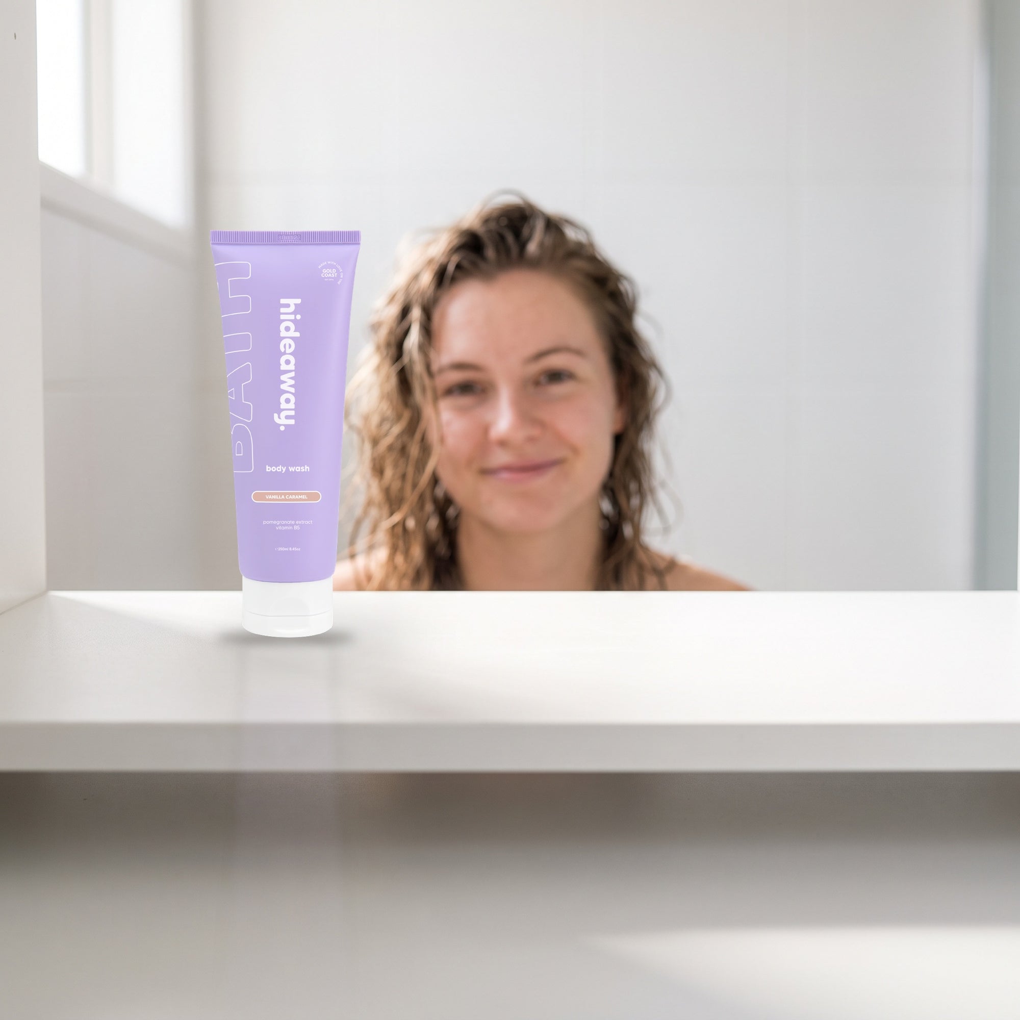 hideaway. Vanilla Caramel Body Wash on a white shelf in a bright tiled bathroom