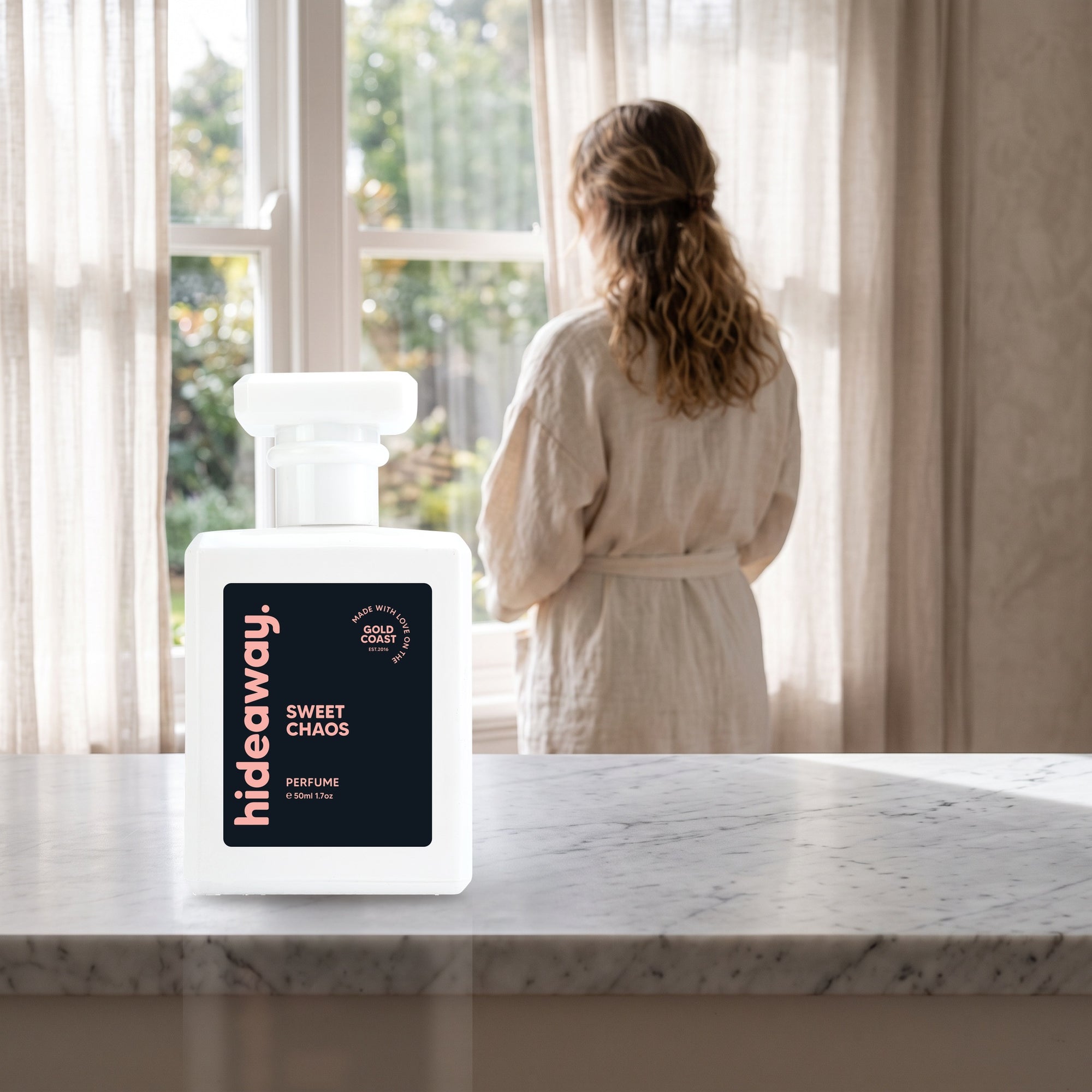 hideaway. Sweet Chaos perfume 50ml bottle on a marble ledge by a sunlit window