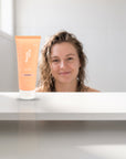 hideaway. Mini Black Essence Hair Mask on a white shelf in a bright tiled bathroom