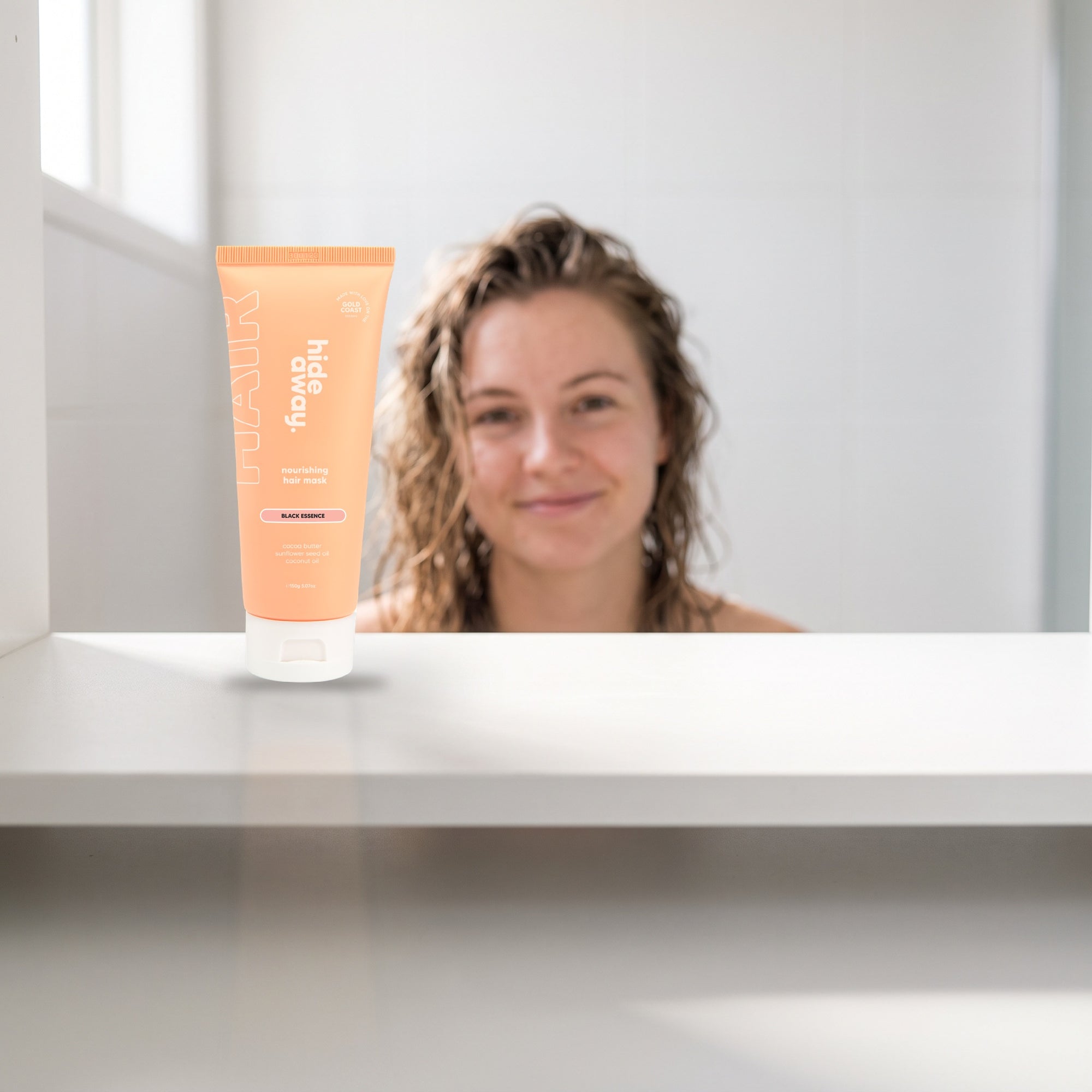 hideaway. Mini Black Essence Hair Mask on a white shelf in a bright tiled bathroom