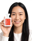 A smiling woman holding Hideaway. Alter Ego perfume