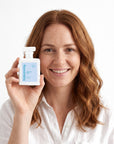 A smiling woman holding Hideaway. Amalfi Air perfume