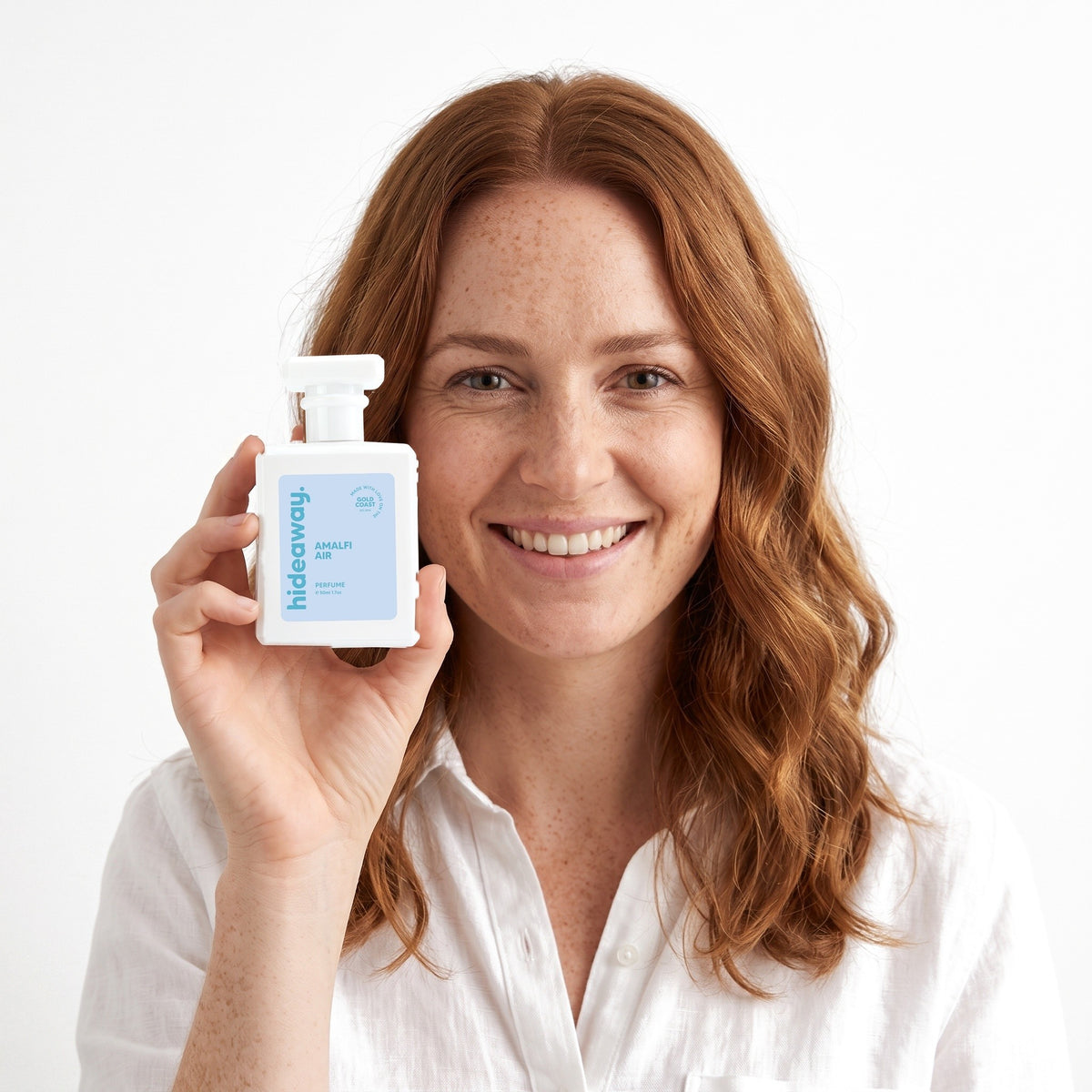 A smiling woman holding Hideaway. Amalfi Air perfume