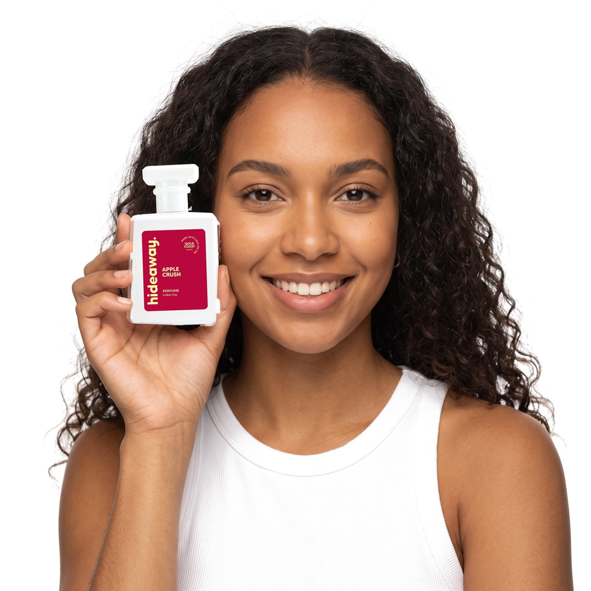 A smiling woman holding Hideaway. Apple Crush perfume