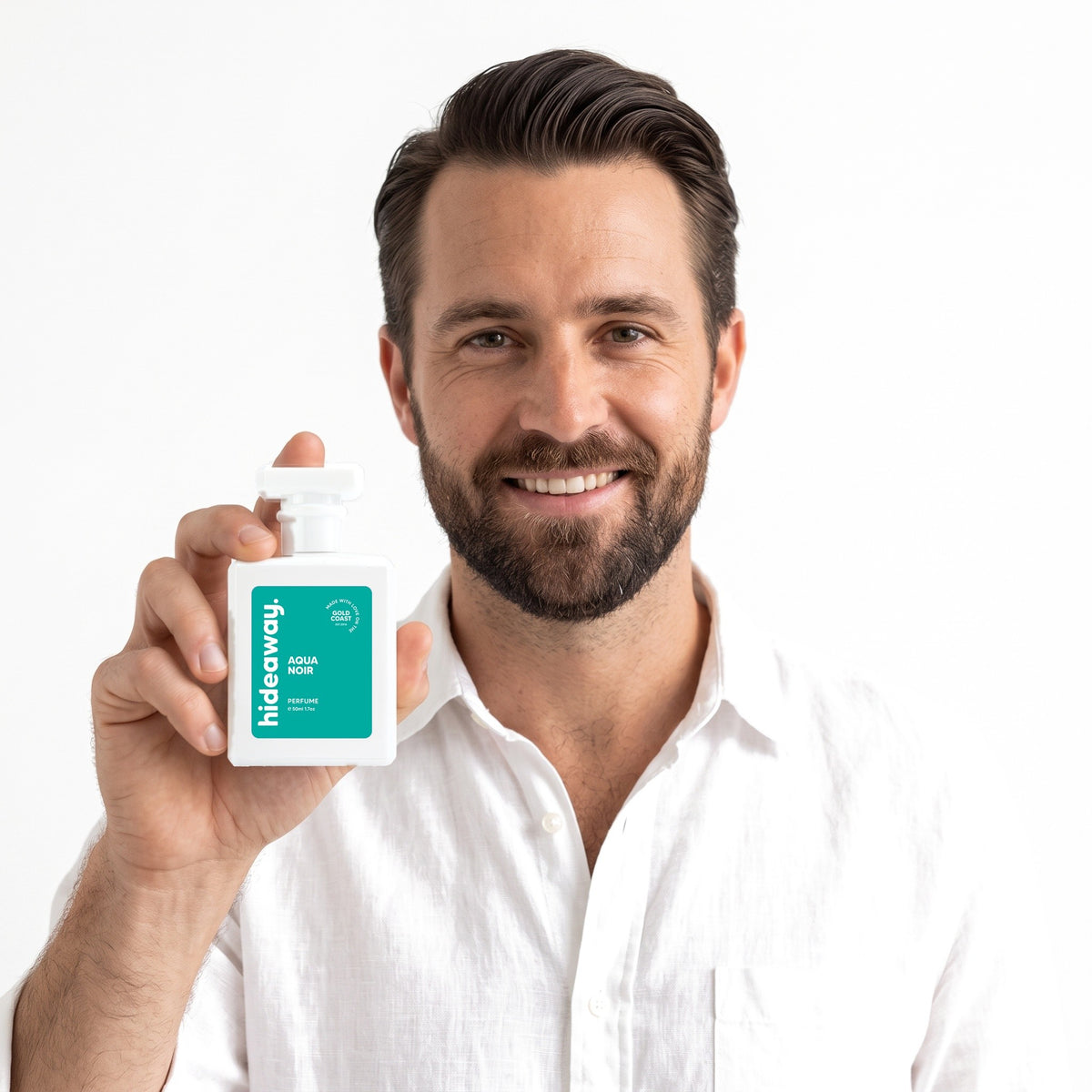 A smiling man holding Hideaway. Aqua Noir perfume