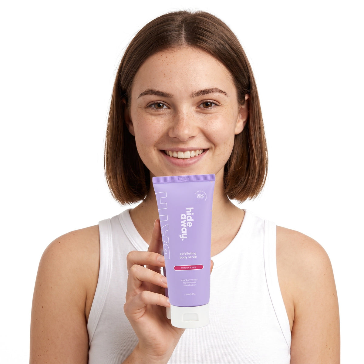 A smiling woman holding Hideaway. Aurora Rouge exfoliating body scrub