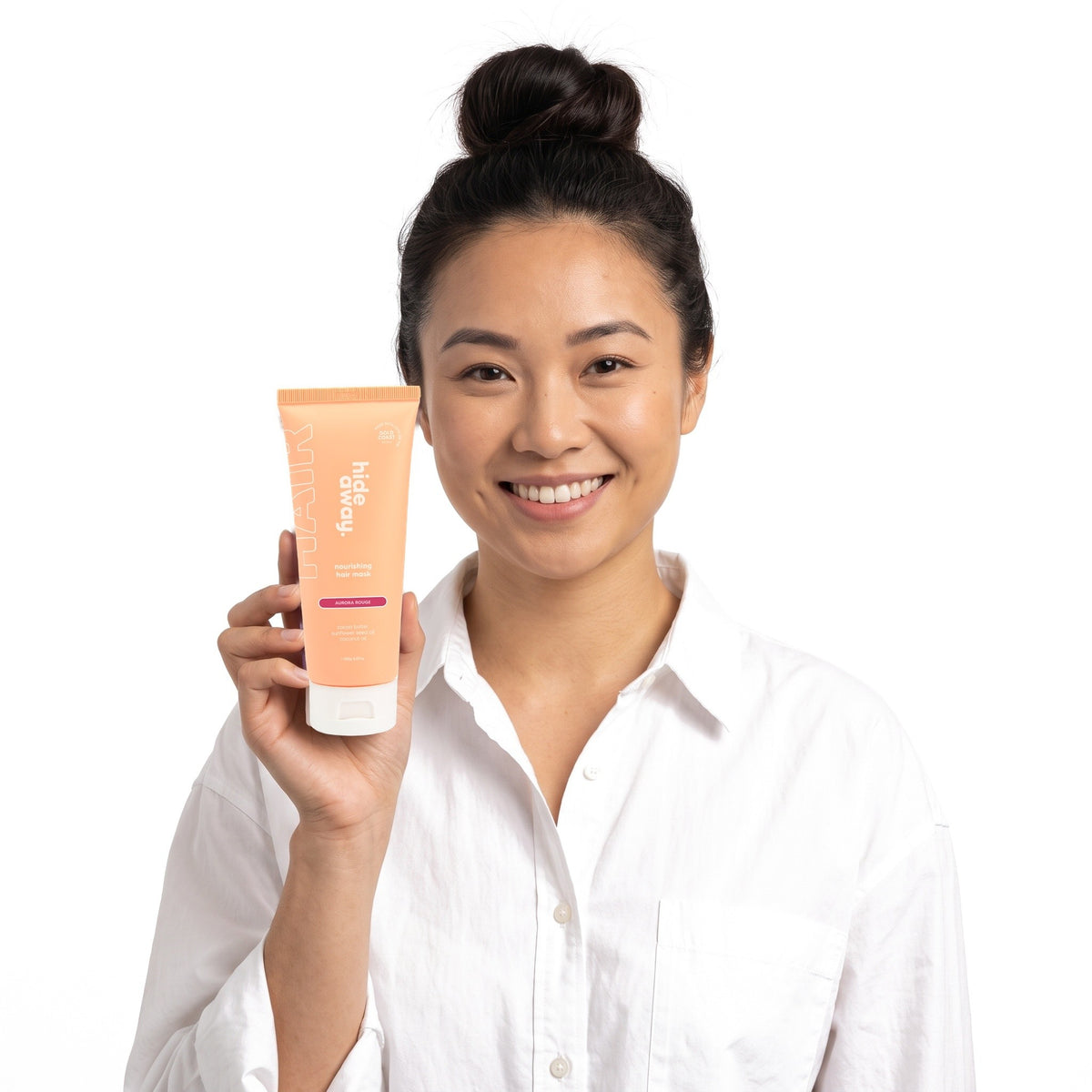 A smiling woman holding Hideaway. Aurora Rouge hair mask