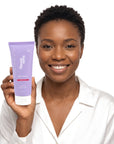 A smiling woman holding Hideaway. Aurora Rouge shower mousse