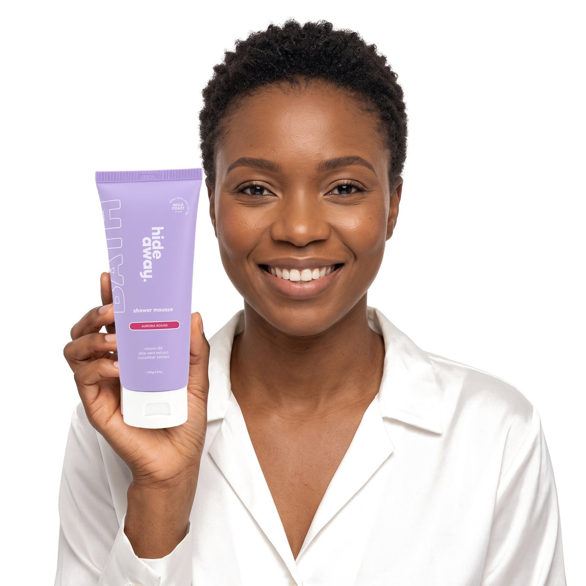 A smiling woman holding Hideaway. Aurora Rouge shower mousse
