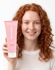 A smiling woman holding Hideaway. Black Essence body custard