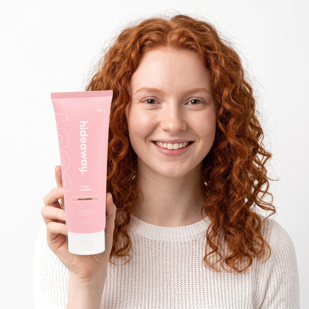 A smiling woman holding Hideaway. Black Essence body custard