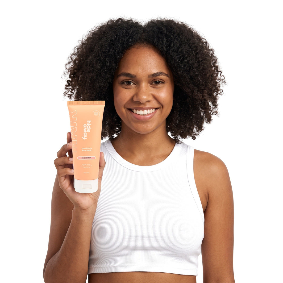 A smiling woman holding Hideaway. Black Essence hair mask