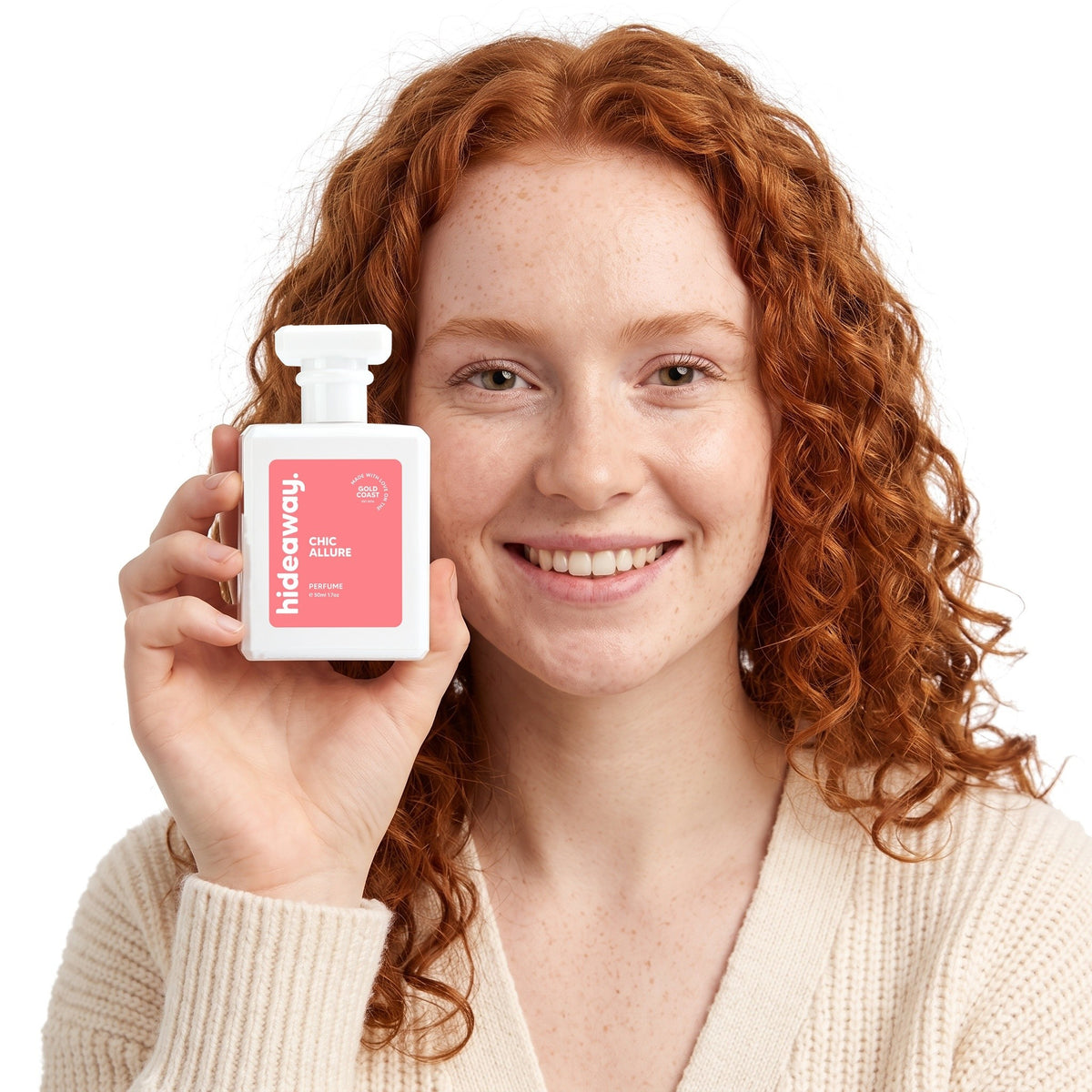 A smiling woman holding Hideaway. Chic Allure perfume