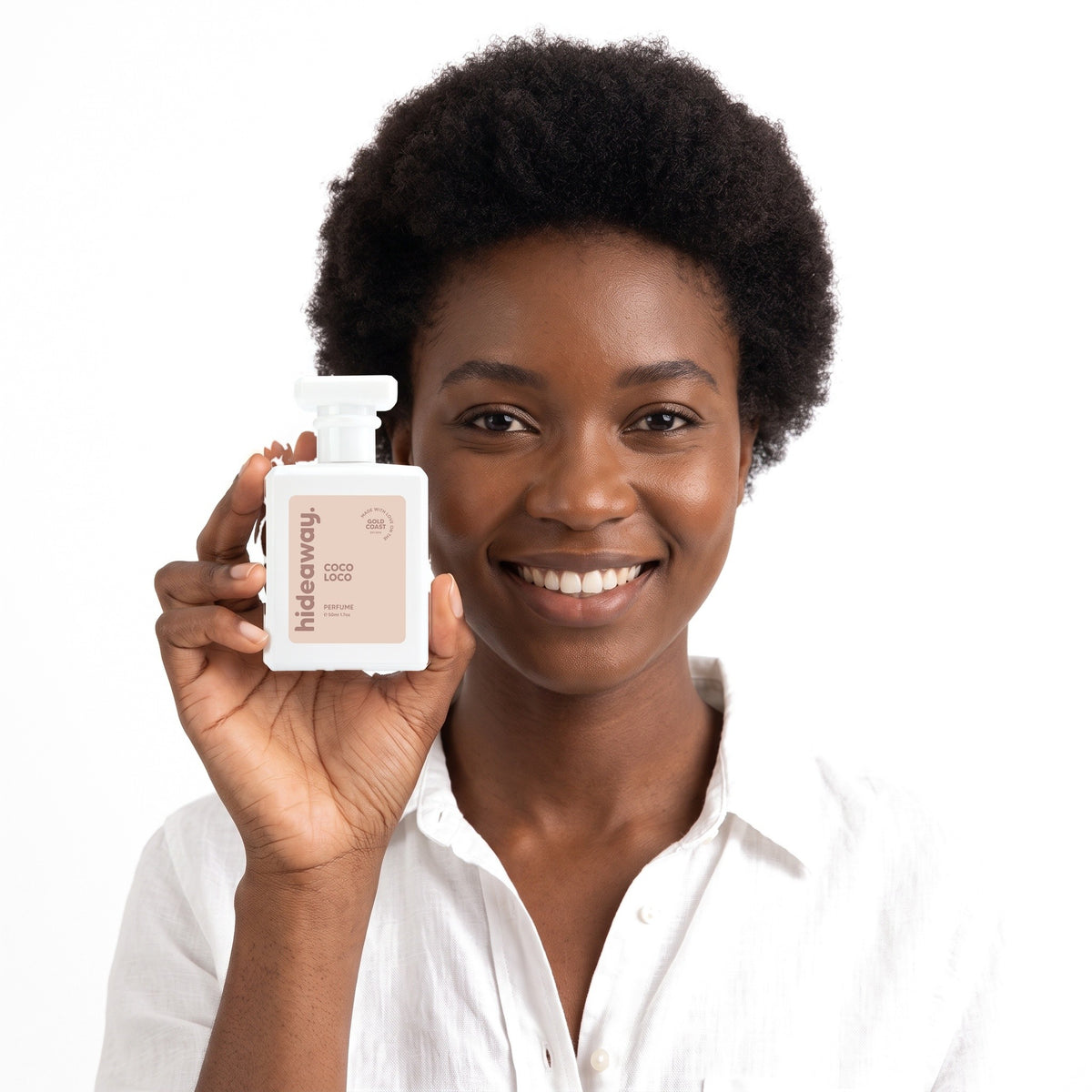 A smiling woman holding Hideaway. Coco Loco perfume