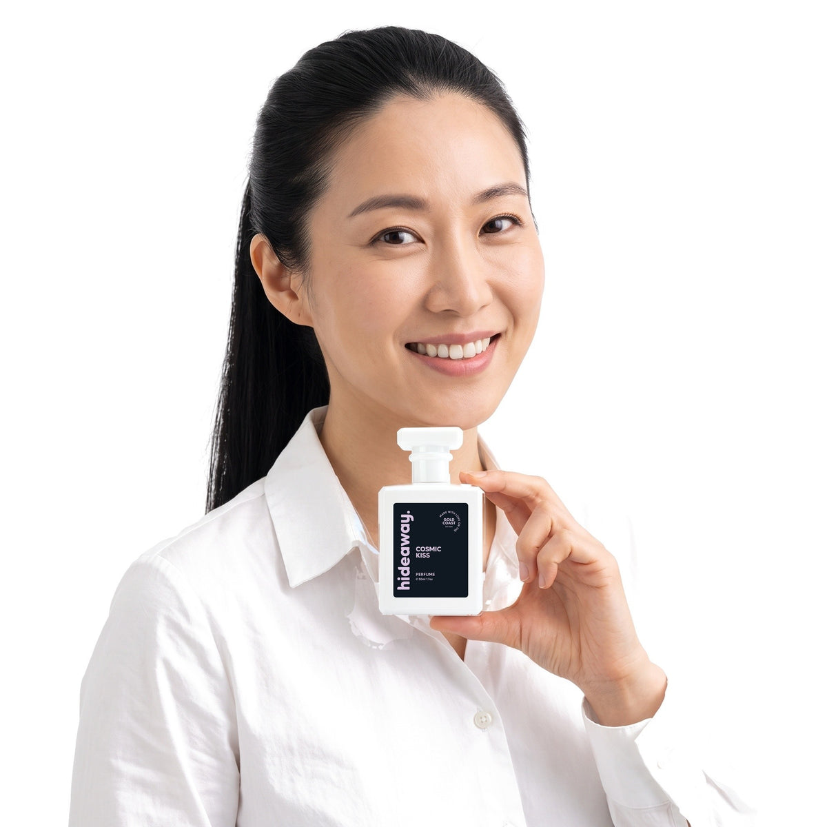 A smiling woman holding Hideaway. Cosmic Kiss perfume