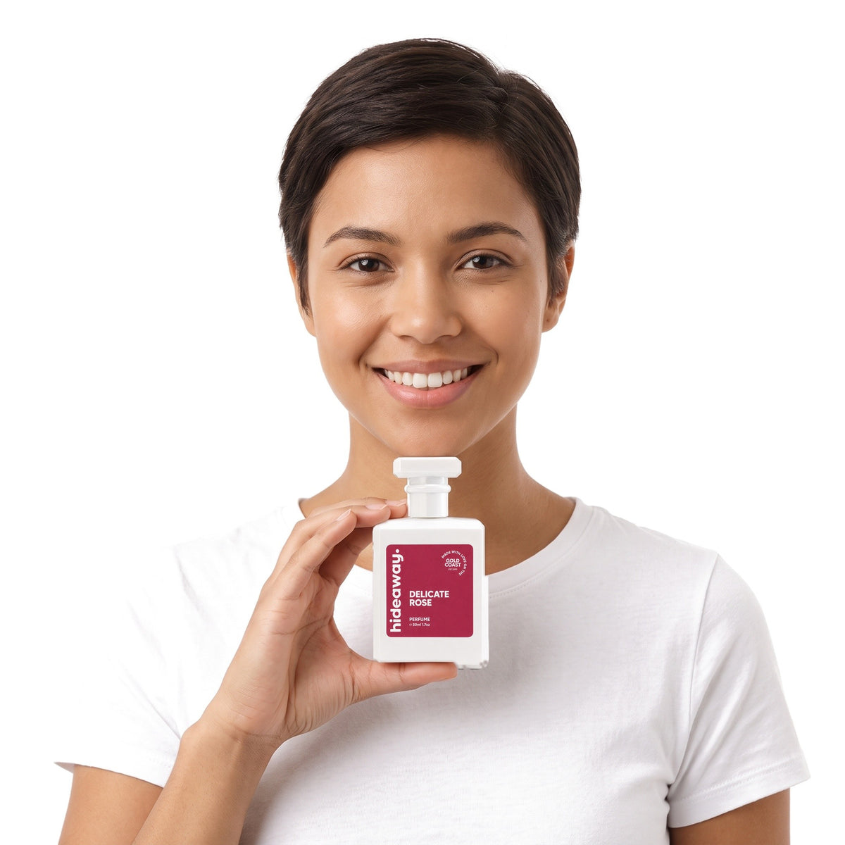 A smiling woman holding Hideaway. Delicate Rose perfume