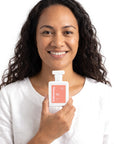A smiling woman holding Hideaway. Fairy Tears perfume