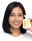 A smiling woman holding Hideaway. Flora Fever perfume