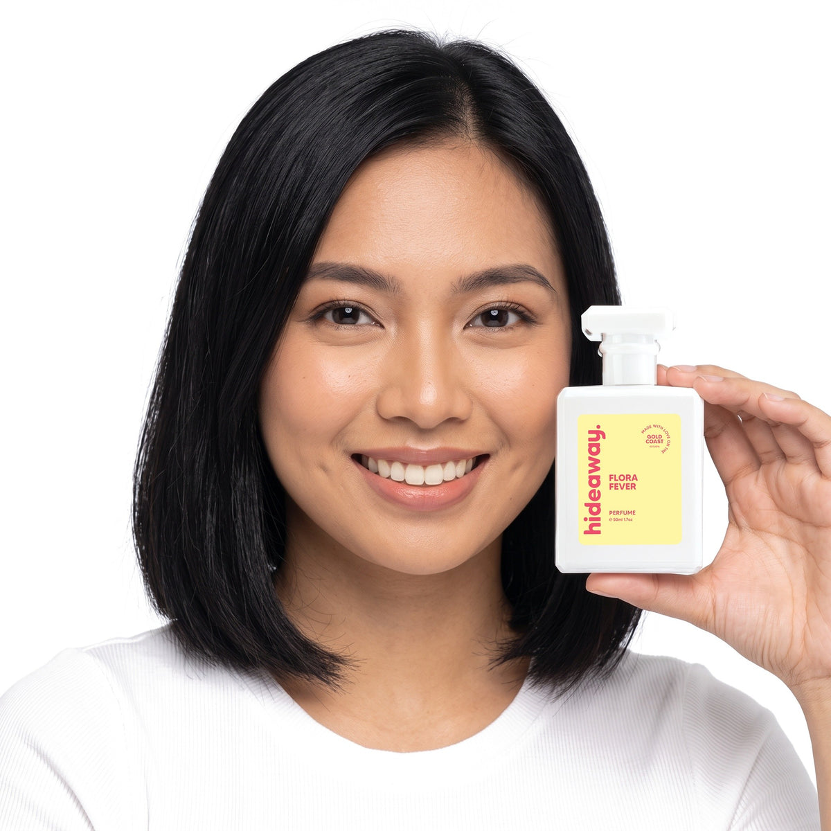 A smiling woman holding Hideaway. Flora Fever perfume